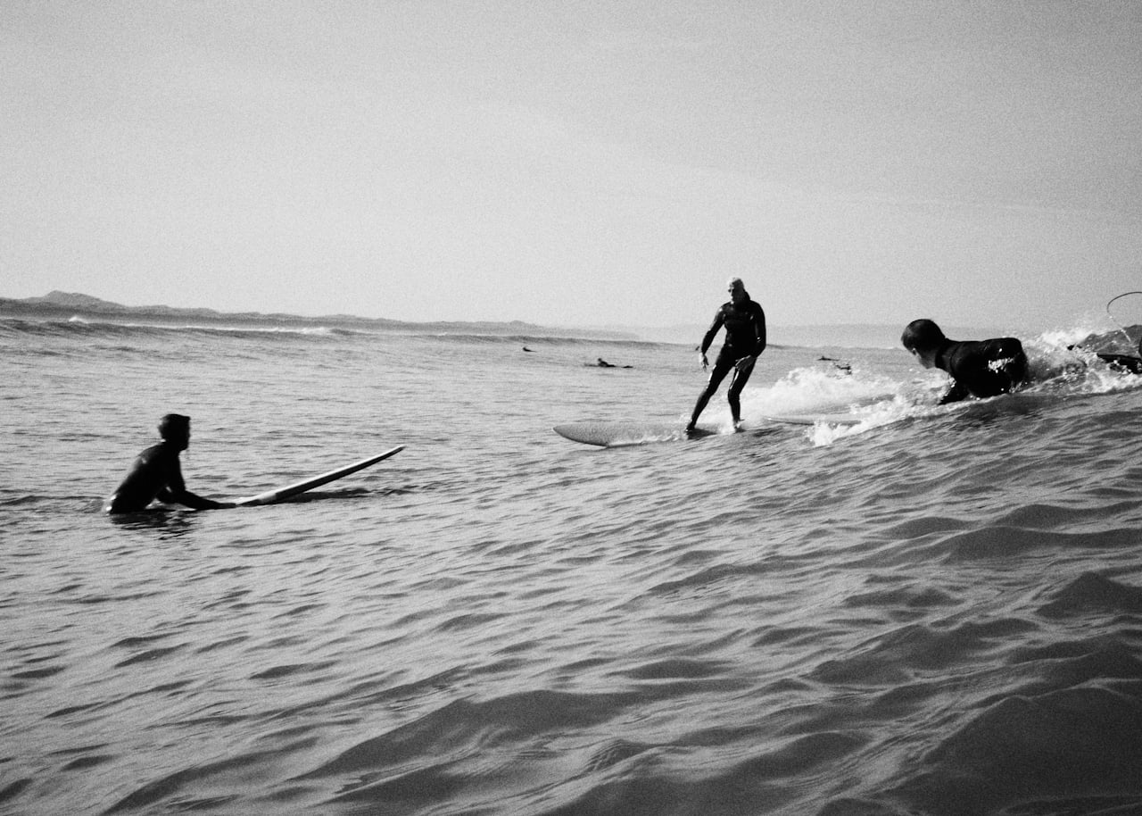 Surfers in black wetsuits as they await the next big wave.